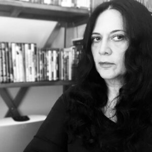 Roudi Boroumand in black and white, in front of a media shelf