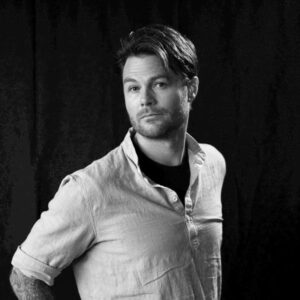 Black and white portrait of Winston Moon, wearing a button-down shirt over a dark t-shirt.